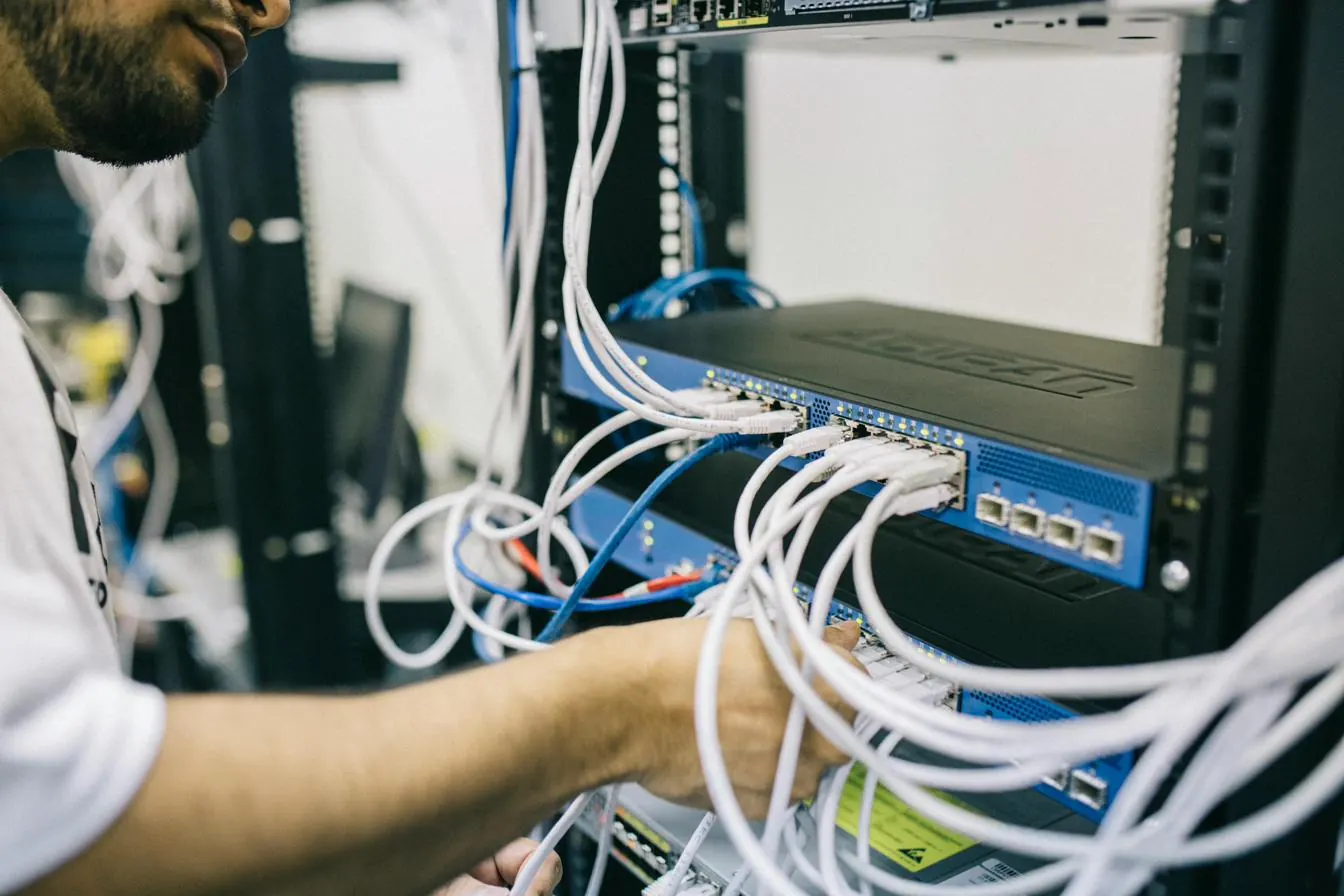 Technicien raccordant des câbles réseau sur un switch installé en baie